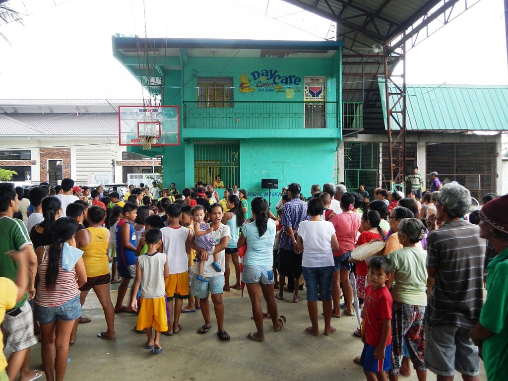 Families gathered at a barangay covered court for an outreach day